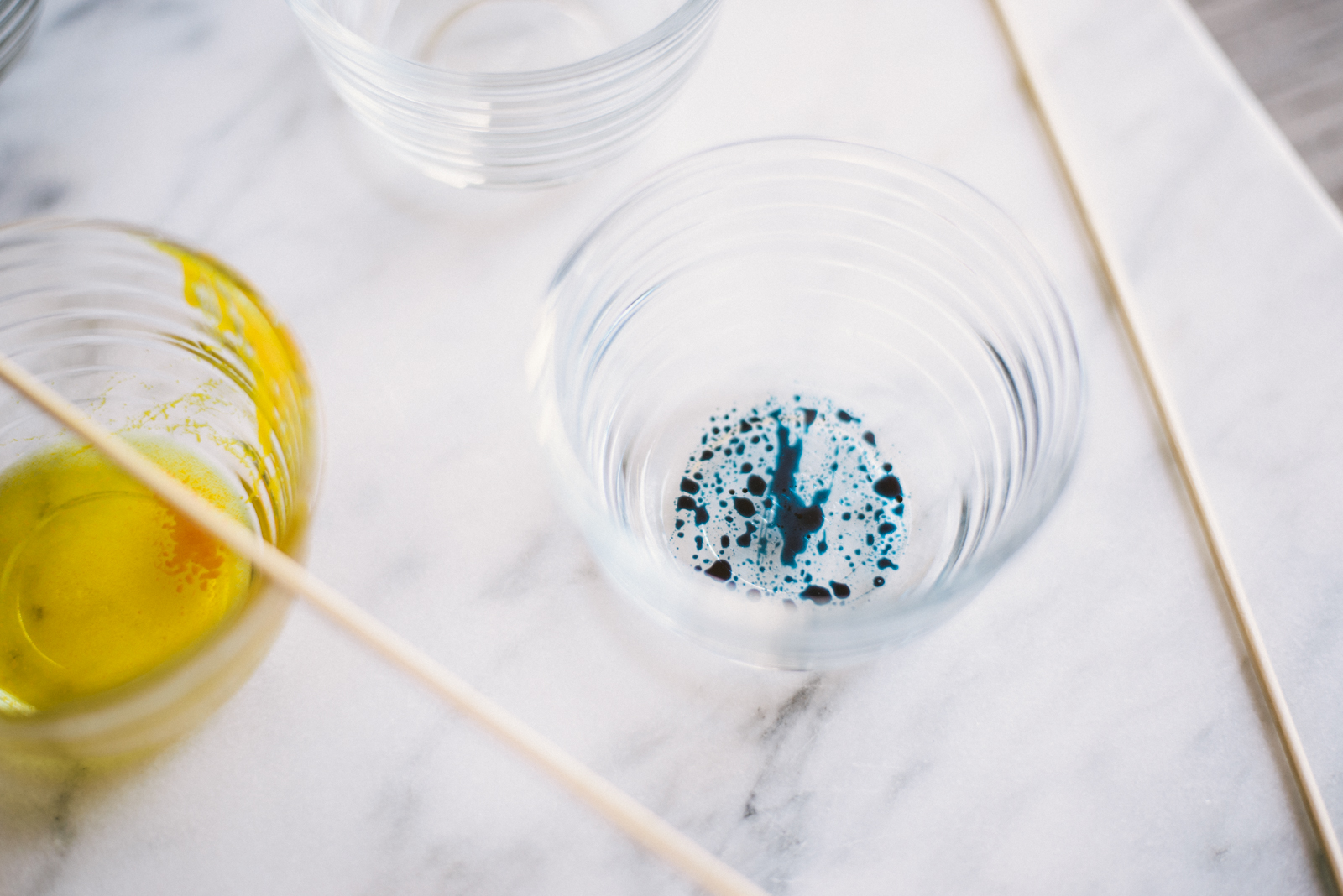essential oils mixed with vegetable oil and natural food coloring in glass bowls on marble