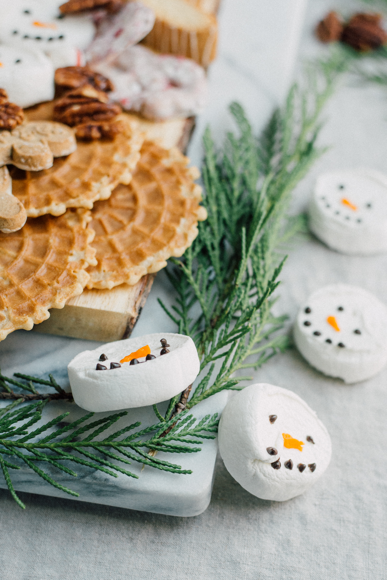 christmas dessert marble board with fresh greens cookies and marshmallow snowmen