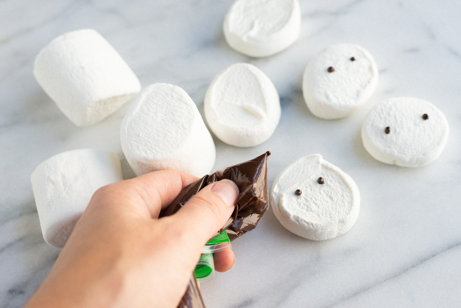 painting snowmen faces on marshmallows with candy melts and ziplock bag