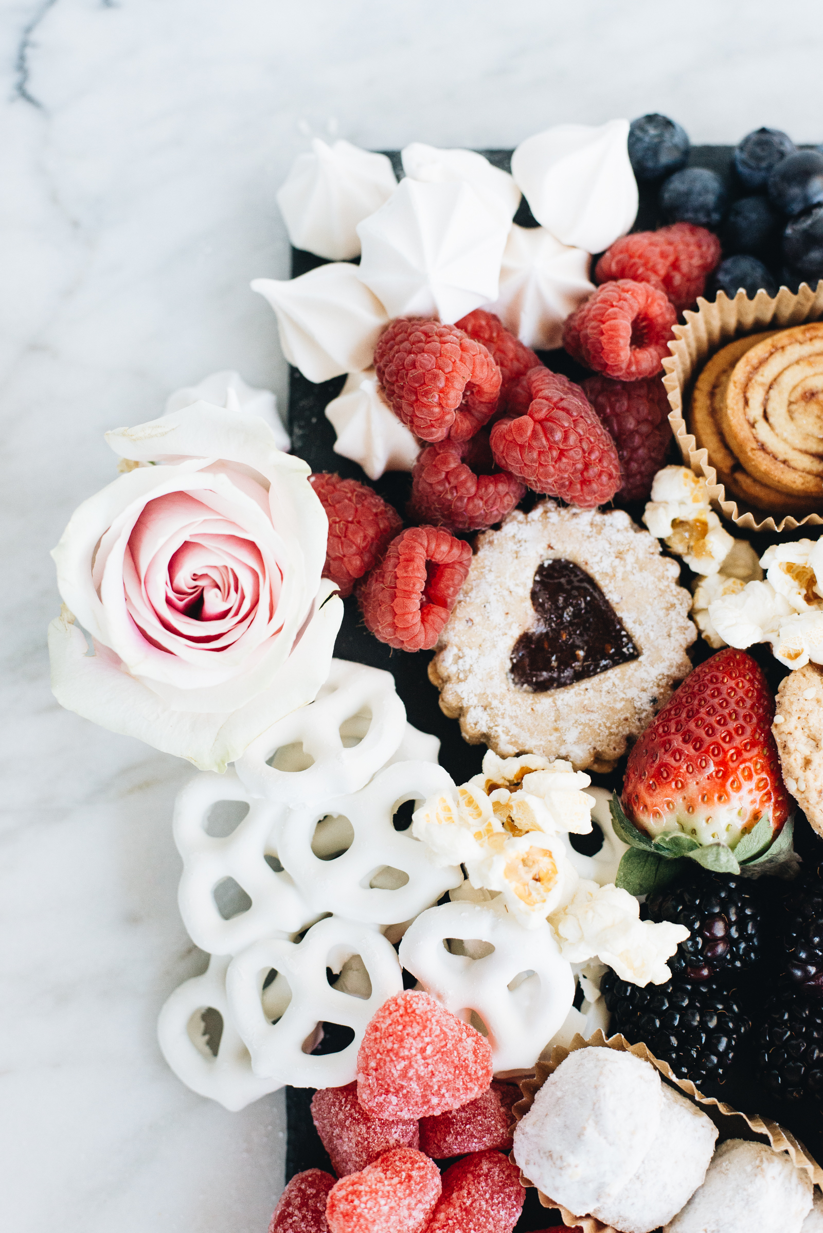 valentine's day dessert board with chocolate covered pretzels, raspberries, blueberries, and gluten-free cookies casey wiegand
